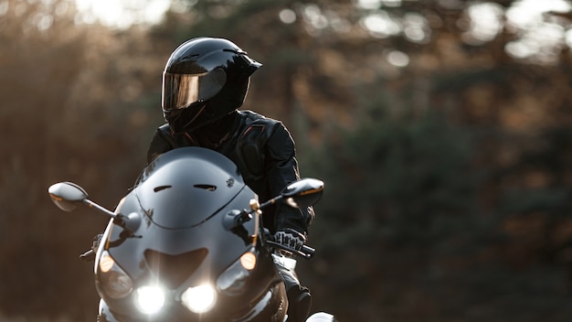 El conductor de una motocicleta deportiva con un casco protector mira hacia un lado con los faros encendidos. Copie el espacio para su texto personalizado