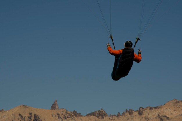 Conductor de parapente de espaldas yendo hacia las montañas