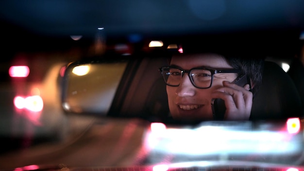 El conductor con el teléfono se refleja en una foto nocturna del espejo retrovisor
