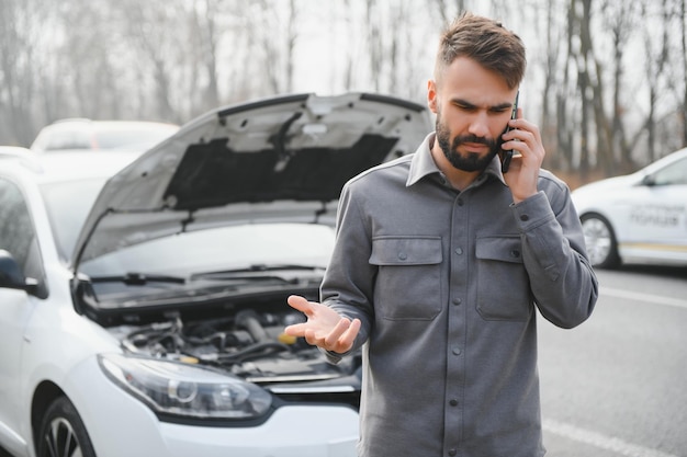 Conductor triste llamando al servicio de automóviles abriendo el capó con problemas de motor parado cerca de un automóvil roto en la carretera Concepto de avería del automóvil