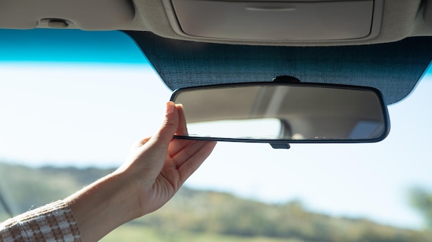 Conductora ajustando el espejo y conduciendo el coche