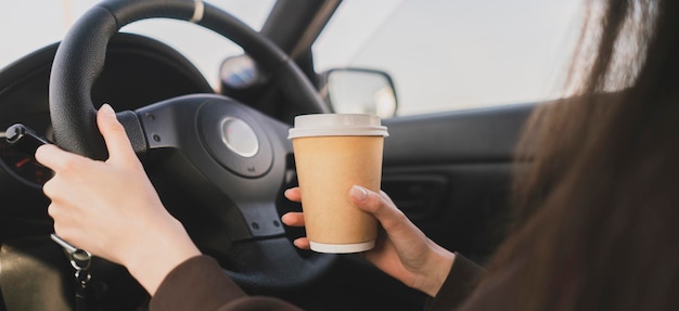 Una conductora descuidada que sostiene una taza de café mientras conduce un automóvil