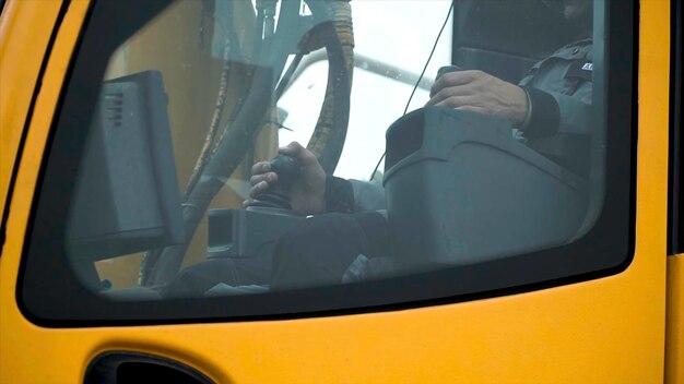 Los conductores de una grúa amarilla que trabajan en un sitio de construcción trabajan el conductor del brazo de la grúa