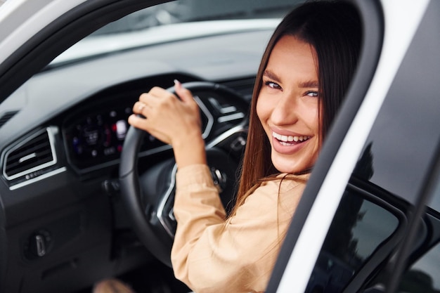 Conduzindo o carro mulher jovem e bonita na moda e seu automóvel moderno