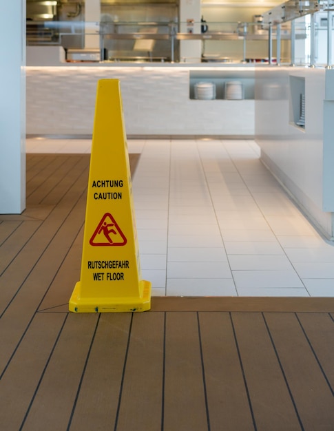 Foto cone de aviso amarelo para piso molhado em inglês e alemão