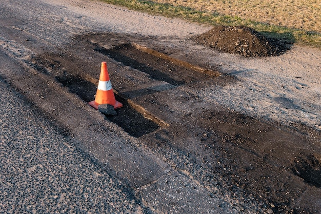 Cone de perigo de tráfego laranja branco na reparação de estradas de asfalto