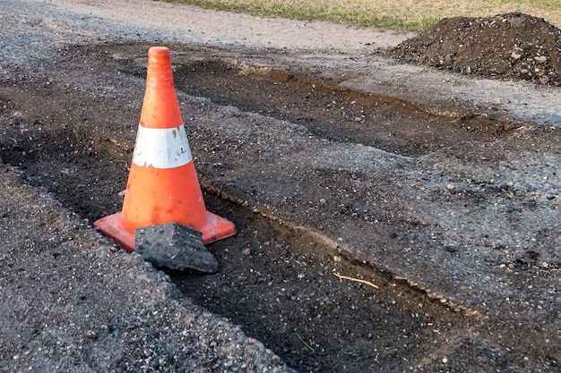 Foto cone de perigo de tráfego laranja branco na reparação de estradas de asfalto