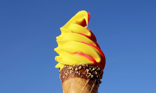 Cone de sorvete macio com sabor de abacaxi e framboesa no céu azul vívido