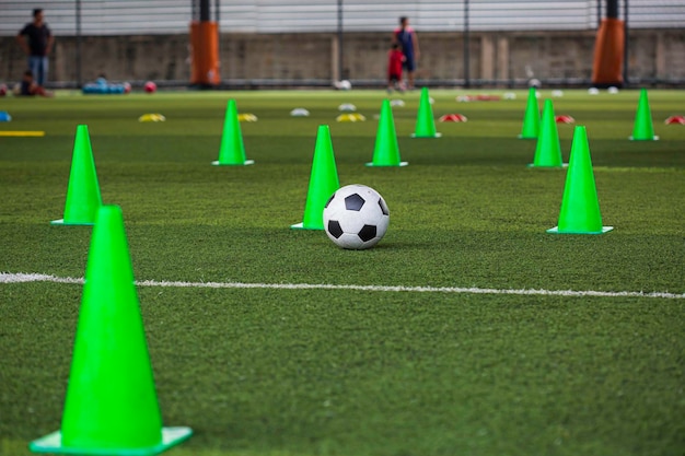 Cone de táticas de bola de futebol no campo de grama com fundo de treinamento Treinamento de crianças no futebol