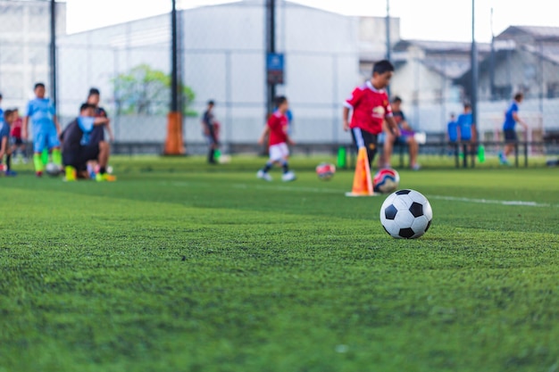 Cone de táticas de bola de futebol no campo de grama com fundo de treinamento.