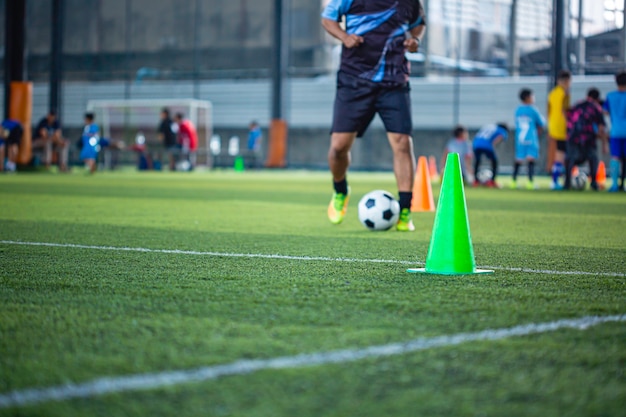 Cone de táticas de bola de futebol no campo de grama com fundo de treinamento