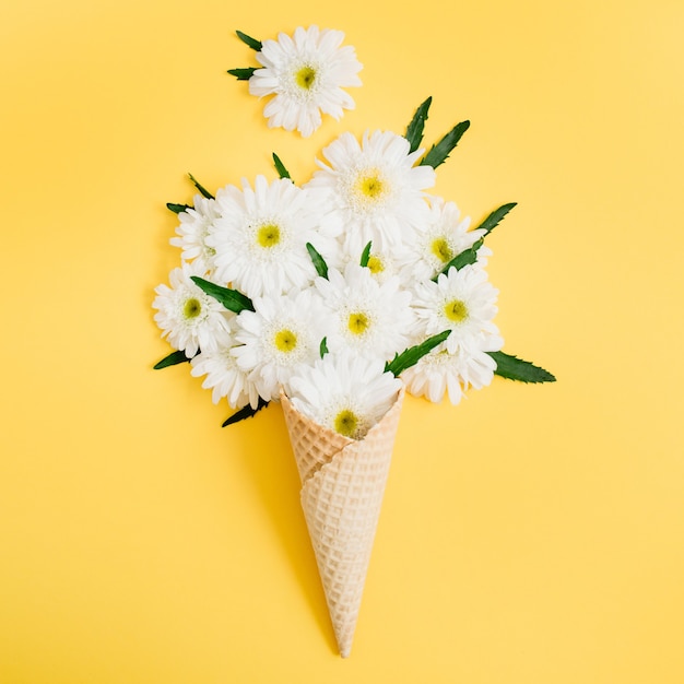 Cone de waffle com buquê de flores de camomila em amarelo