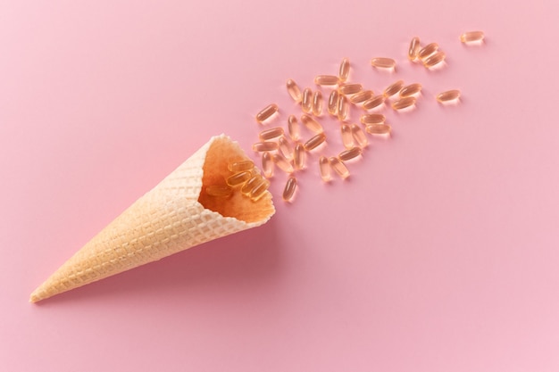 Foto cone de waffle com cápsulas de ômega-3 em fundo rosa. close up, vista de cima. o conceito de saúde, vitaminas, imunidade