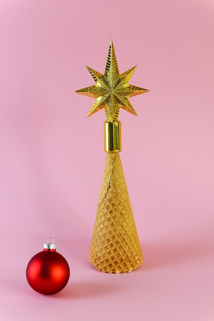 Cone waffle em forma de árvore de Natal com uma estrela em uma superfície rosa.