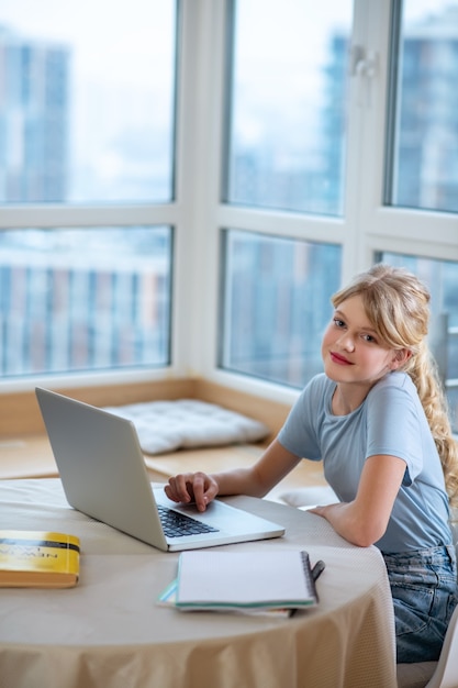 Conectado. Una chica bonita rubia sentada en la computadora portátil