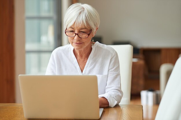 Conectado a la información desde la comodidad del hogar Foto de una anciana usando una computadora portátil