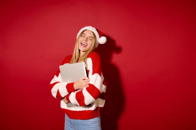 Conectado. Uma garota com um chapéu de Papai Noel com um laptop