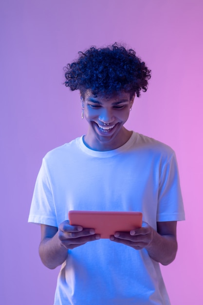 Foto conectados. jovem de cabelos cacheados segurando um tablet e parecendo envolvido