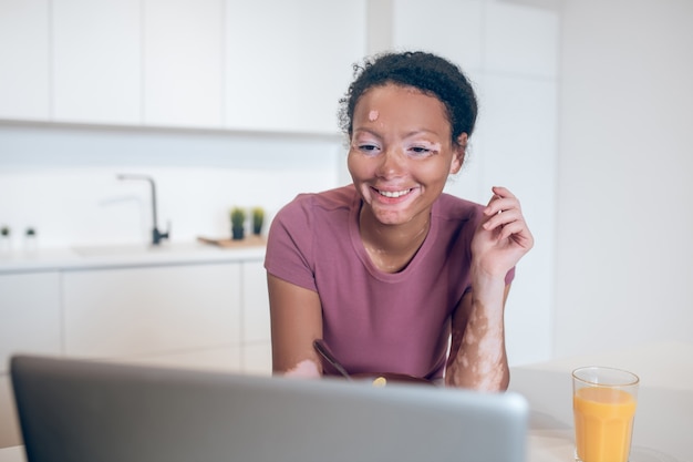 Conectados. jovem mulata na cozinha assistindo algo na internet e sorrindo