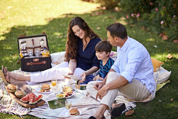 Conectados mientras hacen un picnic Foto de una familia disfrutando juntos de un picnic