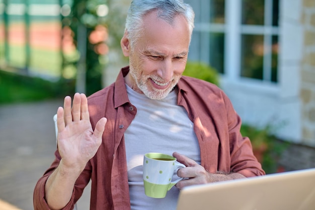 Conectados. Um homem de camisa cor de vinho com um laptop nas mãos