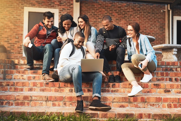 Conectando-se com jovens que pensam como você Foto de um grupo de estudantes usando um laptop juntos no campus