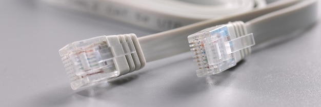 Conectores de Internet blancos colocados en un cable de superficie gris con clip de plástico en la punta