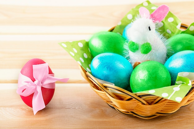 Conejito de juguete en canasta con huevo decorado