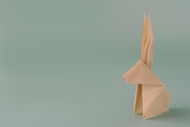 Conejito de origami de papel sobre un fondo azul pastel Manualidades hechas de papel El concepto mínimo de Pascua o el año del conejo Espacio de copia de conejito de Pascua