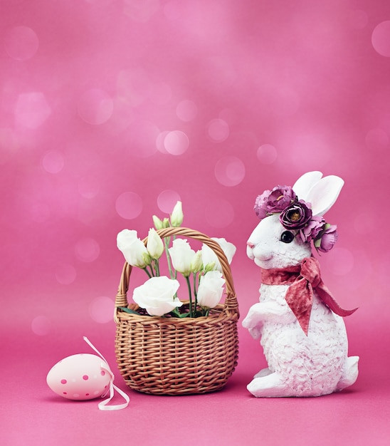 Foto conejito de pascua con una canasta de flores blancas. tarjeta de felicitación de pascua feliz