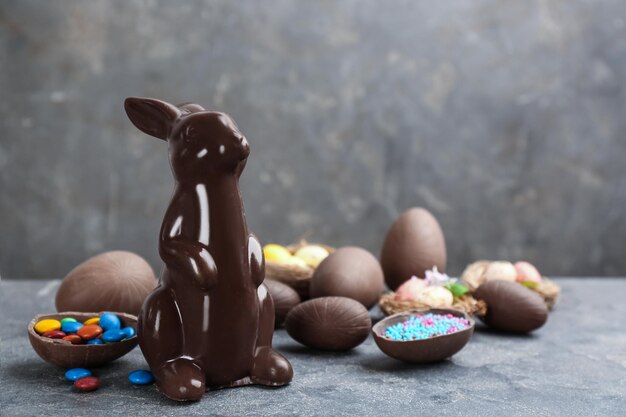 Foto conejito de pascua de chocolate y huevos en mesa gris espacio para texto