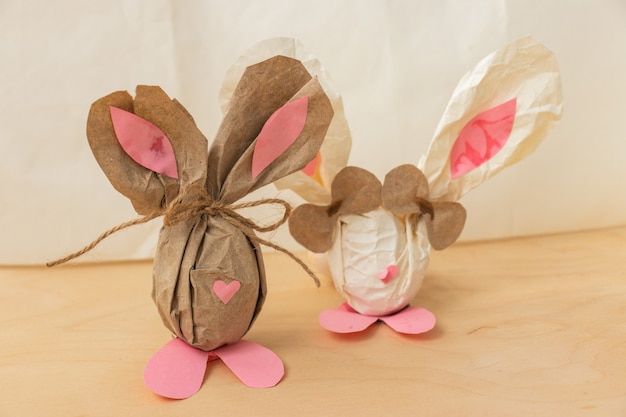 Conejito de Pascua hecho de un huevo de gallina marrón y papel artesanal en manos de una niña, primer plano