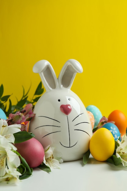 Conejito de Pascua, huevos y flores de alstroemeria sobre fondo amarillo