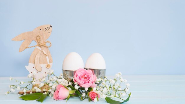 Conejito de Pascua de madera y huevos decorados con flores.