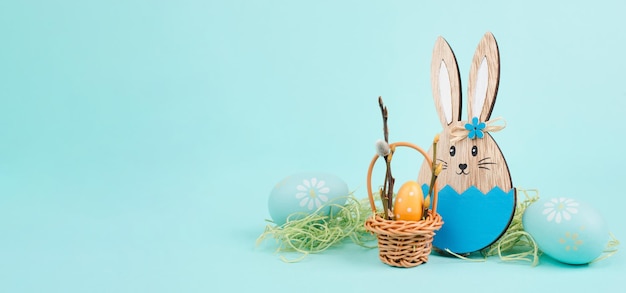 Conejito de pascua o conejo sentado junto a una canasta de mimbre llena de huevos coloridos, vacaciones de primavera