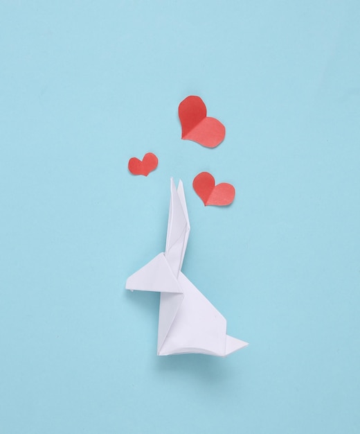 Conejito de pascua de origami con corazones sobre fondo azul