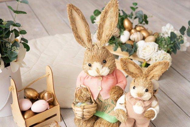 Conejitos de heno de Pascua madre e hijo en una composición decorativa de Pascua huevos flores