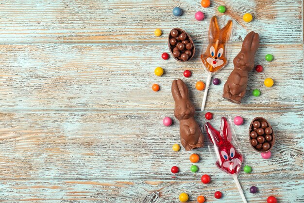 Foto conejitos de pascua de chocolate y caramelos sobre fondo de madera