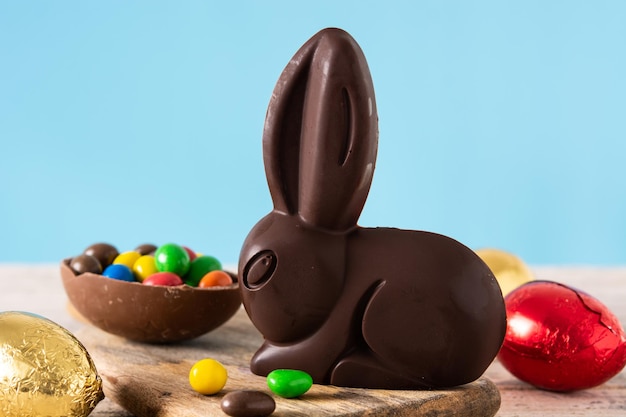 Conejo de chocolate de Pascua y huevos de colores en una mesa de madera