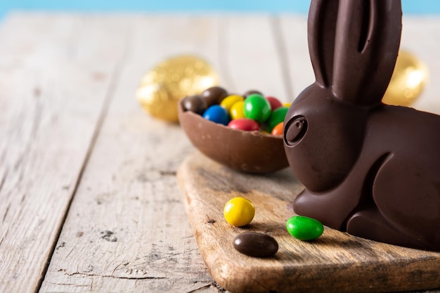 Conejo de chocolate de Pascua y huevos de colores en una mesa de madera