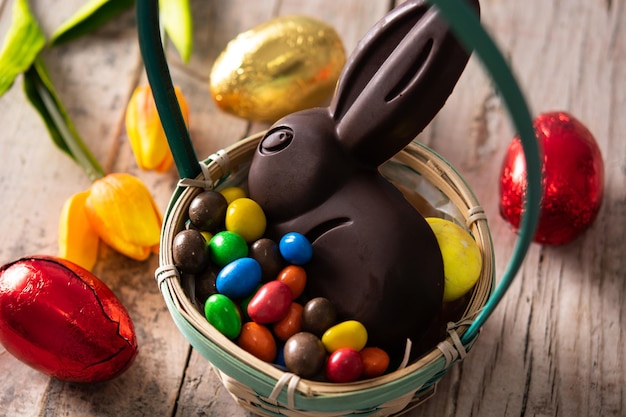 Conejo de chocolate de Pascua y huevos de colores en una mesa de madera