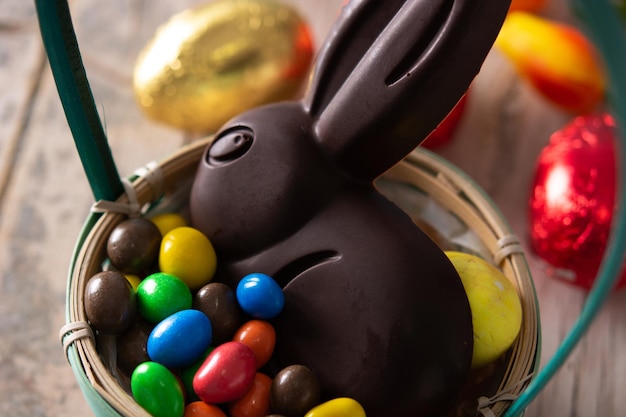 Conejo de chocolate de Pascua y huevos de colores en una mesa de madera