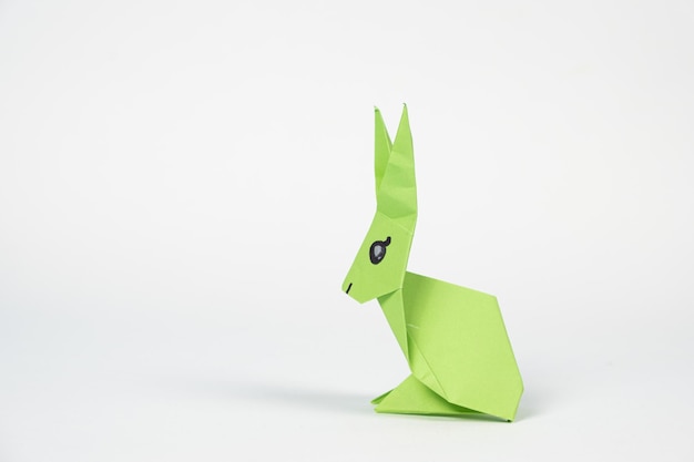Foto un conejo de origami verde sobre un fondo blanco.