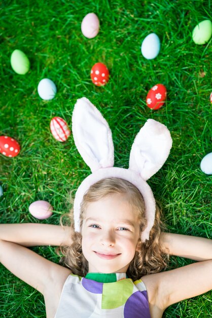 Conejo de Pascua. Niño divirtiéndose al aire libre. Niño jugando con huevos sobre la hierba verde. Concepto de vacaciones de primavera