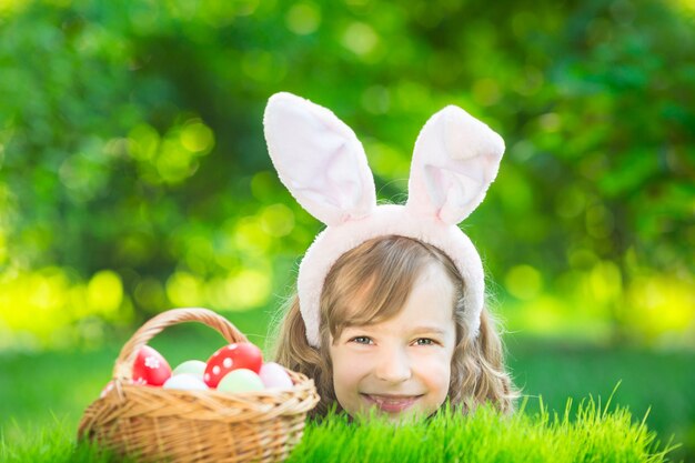 Conejo de Pascua. Niño divirtiéndose al aire libre. Niño jugando con huevos sobre la hierba verde. Concepto de vacaciones de primavera