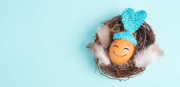 Conejo de Pascua o huevo de conejo en un nido de pájaros orejas y plumas ganchadas color azul de vacaciones de primavera