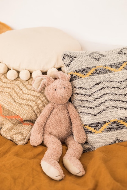 Foto conejo de peluche y almohadas de estilo boho en la cama
