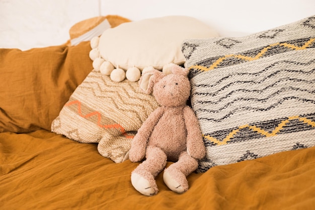 Foto conejo de peluche y almohadas de estilo boho en la cama