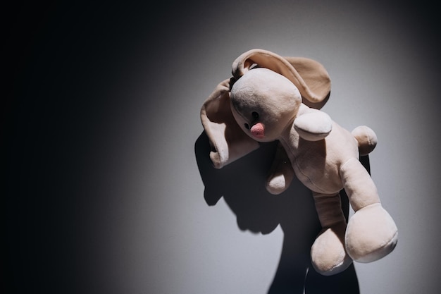Foto el conejo de peluche está solo en una habitación oscura concepto de soledad y violencia de abuso infantil