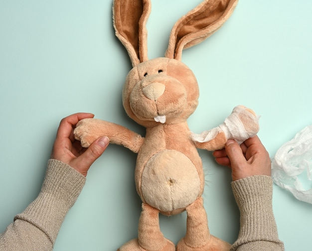 Conejo de peluche suave con una pata vendada con un vendaje médico blanco, trauma
